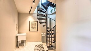 Ein modernes Interieur mit einer Wendeltreppe, einem kleinen Waschbecken und einem gerahmten Kunstwerk an der Wand.