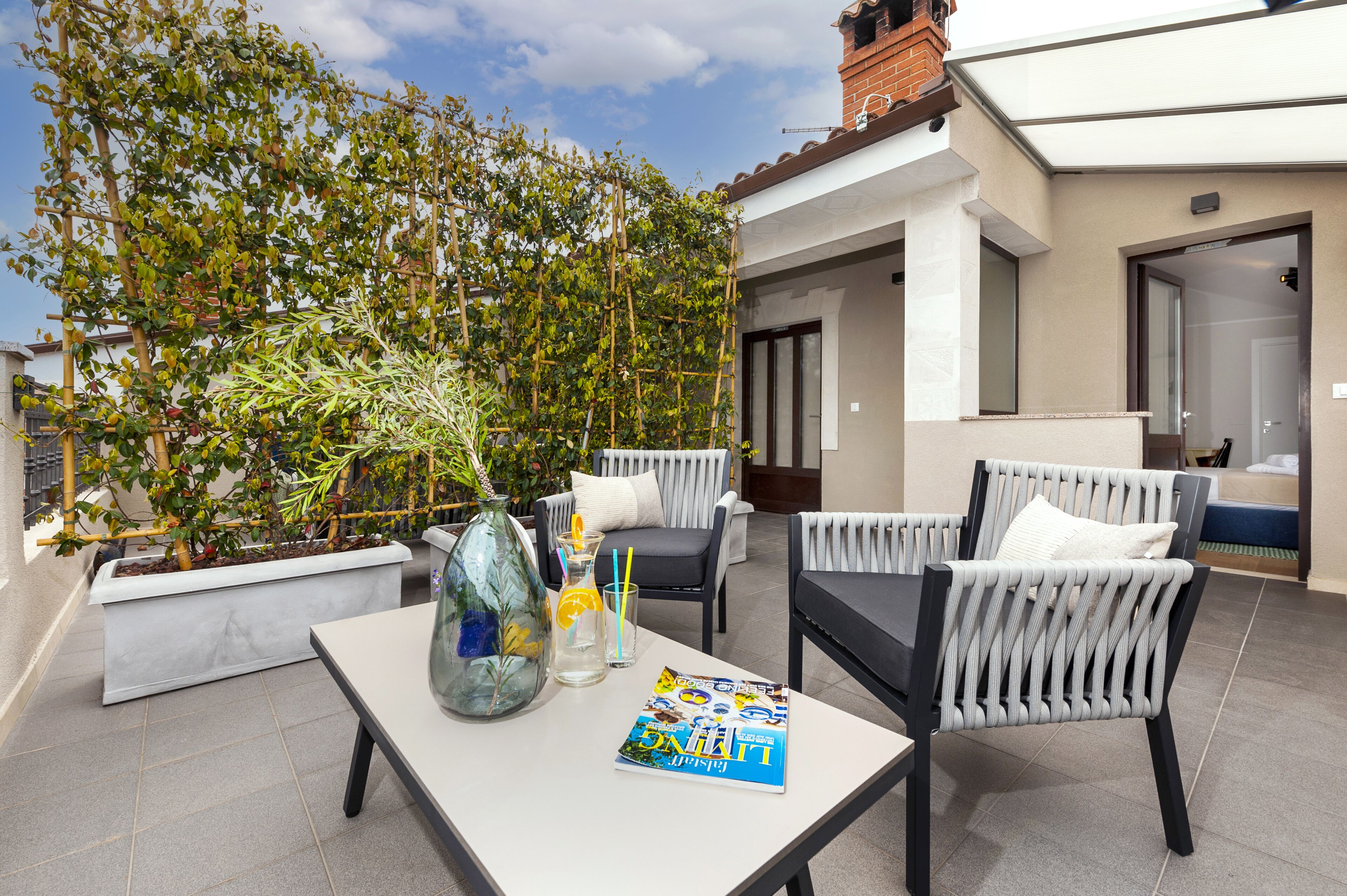 Un área de estar al aire libre moderna con una mesa, sillas y una revista.