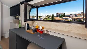 A modern kitchen with a large window, a coffee machine, and two glasses of red drink with orange slices.