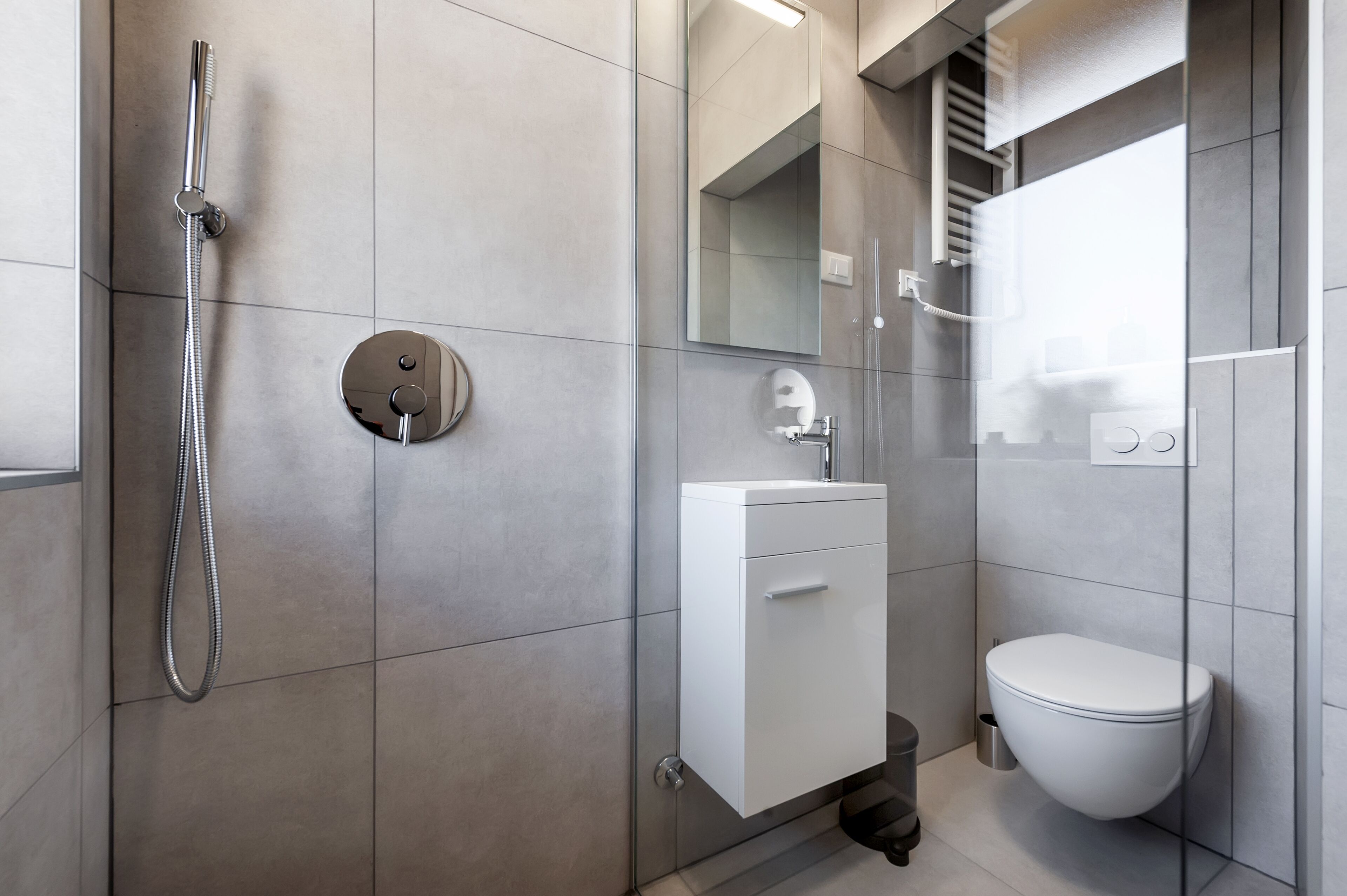 A modern bathroom with a shower, toilet, and sink.
