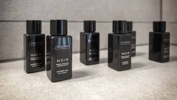 A row of black bottles labeled "NOIR" on a tiled surface.