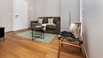 Una sala de estar moderna con un sofá marrón, una mesita redonda pequeña y una silla de madera con asiento de mimbre.