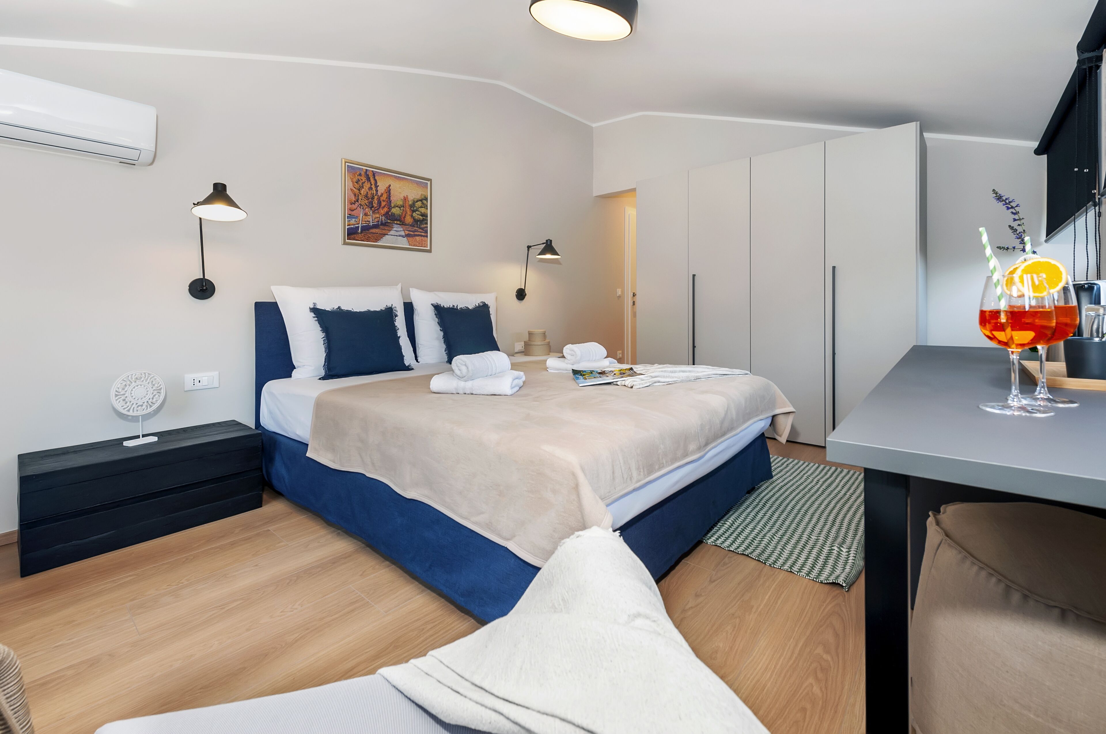 Una habitación de hotel moderna con una cama bien hecha, lámparas de noche, una mesita con una bebida y vistas al pasillo.