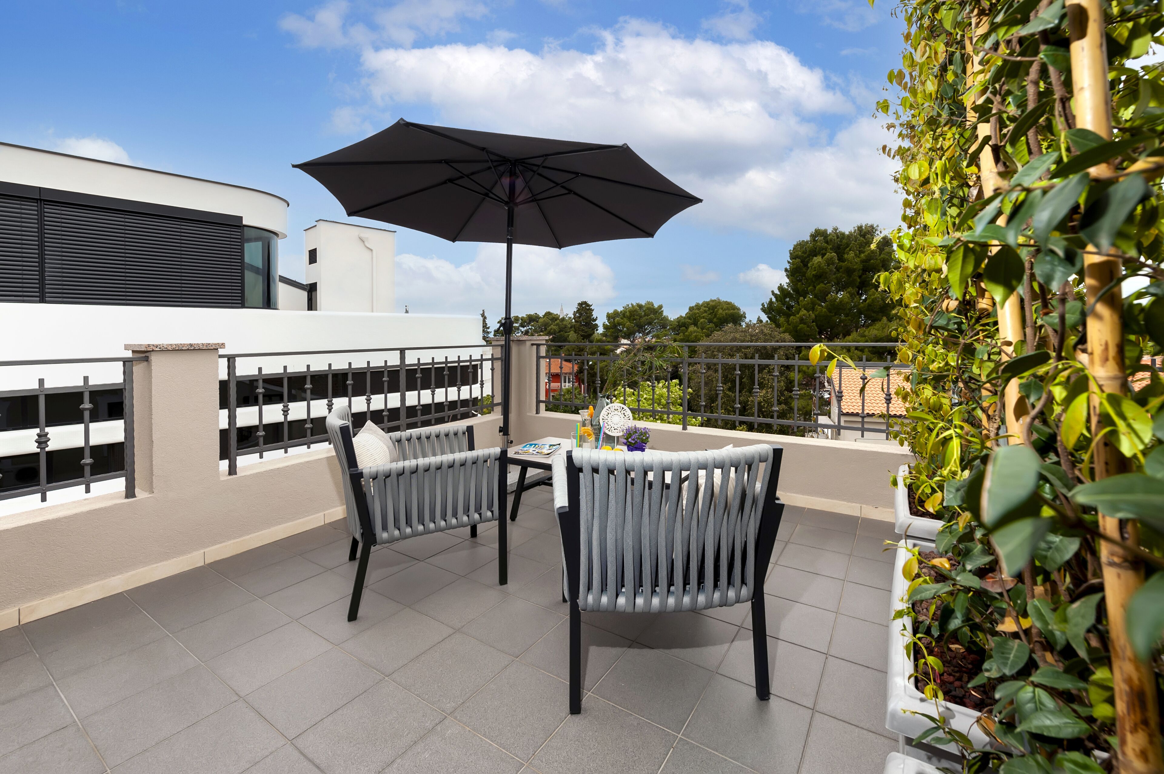 Terraza en la azotea con dos sillas, una mesa y una sombrilla grande.