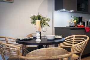 A dining area with a round table, wicker chairs, a vase with a candle, and a potted plant.