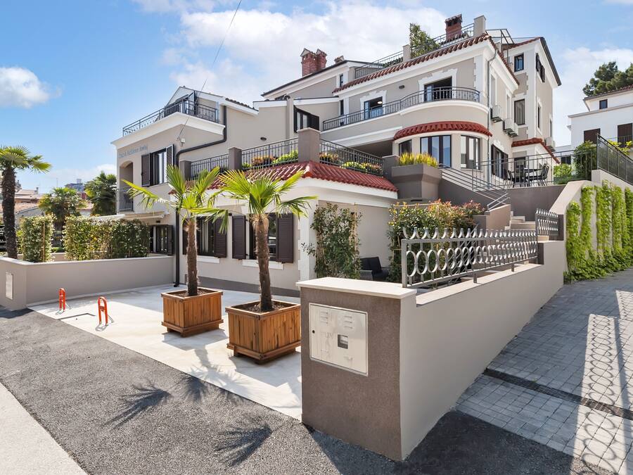 Un hotel de varios pisos con balcones, mobiliario exterior y un jardín ajardinado.