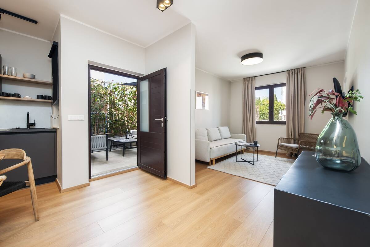 A modern living room with a sofa, coffee table, and a dining area with chairs and a table.