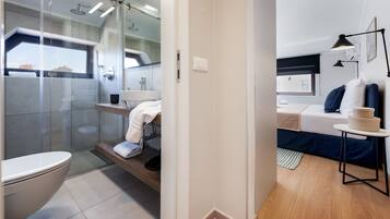 A modern bathroom with a glass shower enclosure, a toilet, and a sink area.