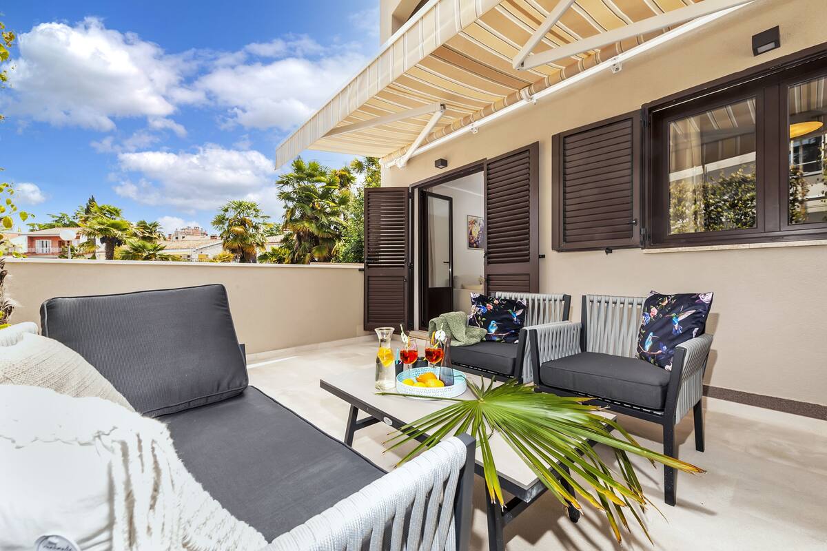 A balcony with two sofas, a table with drinks and fruits, and a potted plant.
