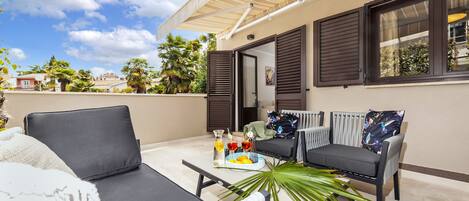 A balcony with two sofas, a table with drinks and fruits, and a potted plant.