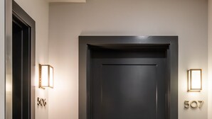 Una porta nera con il numero 506 a sinistra e 507 a destra, affiancata da lampade fissate al muro.