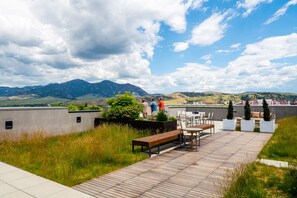An outdoor patio area with a wooden deck, seating, and a view of mountains. - Skyview Penthouse- Luxury penthouse in downtown Bozeman with 30 night minimum (Bozeman)