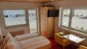 Un dormitorio con cama, escritorio, silla, televisor y armario.