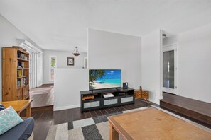 Un salon moderne avec un téléviseur à écran plat, une bibliothèque en bois et une table basse.