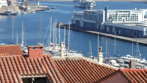 Un puerto con barcos, un faro y un barco grande.