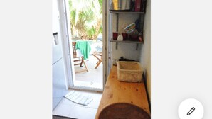 Een keuken met een houten aanrecht, een mand en een deur naar een buitenruimte met een tafel en stoelen.