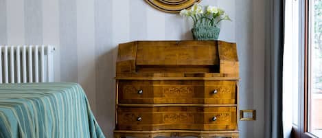 Una habitación con cama, cómoda de madera con cajones, espejo y radiador.