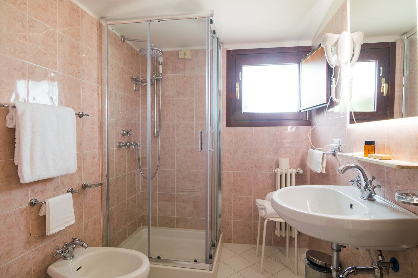 A bathroom with a glass-enclosed shower, a sink, and a mirror.