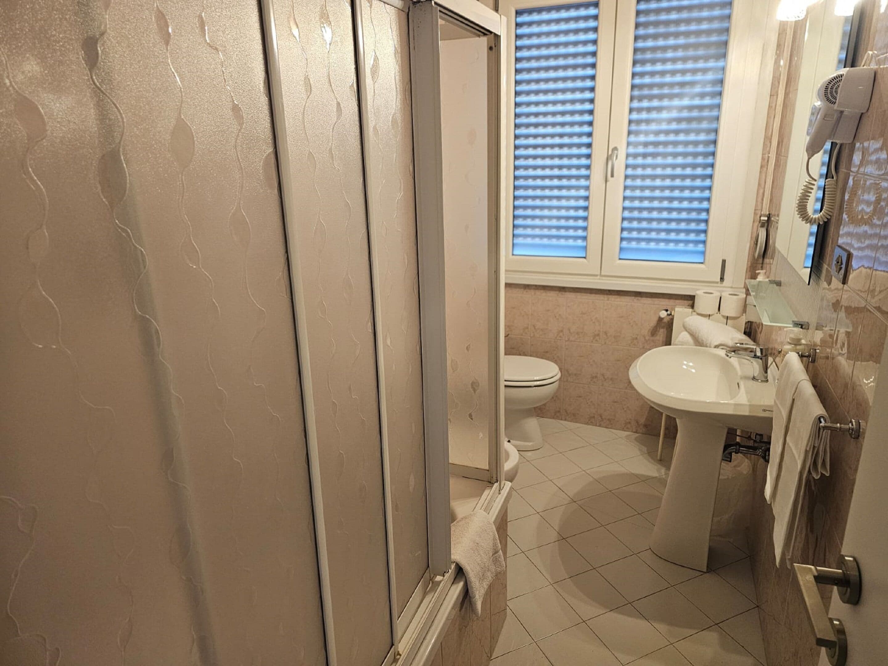 A bathroom with a toilet, sink, and shower area.