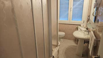 A bathroom with a toilet, sink, and shower area.