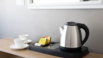 A kitchen counter with a coffee maker, two white cups, and a box of coffee pods.