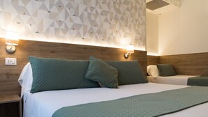 Habitación de hotel con cabecera de madera, dos camas con ropa de cama verde y decoración de pared con motivos geométricos.