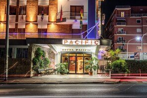 The exterior of the Pacific Hotel with a brick facade, large windows, and a signboard.