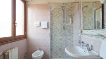 Une salle de bain équipée d’un bidet, d’une douche, d’un lavabo et d’un miroir.