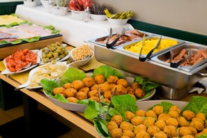 A buffet table with various food items including meats, cheeses, and vegetables.