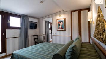 A hotel room with a bed, a chair, a television, a painting, and a decorative wall piece.