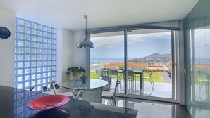 Ein moderner Balkon mit Glastür, Esstisch, Stühlen und einer roten Schale.