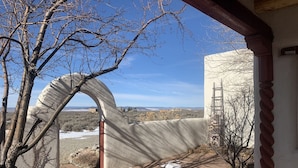 A stone archway leading to a building with a red column, a ladder, and a clear view of the surrounding landscape.