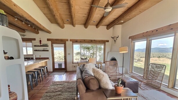 A spacious living area with a large sofa, a dining table, and a view of the desert landscape through large windows.