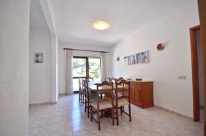 A dining area with a table and chairs, a cabinet, and a window with curtains.