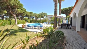 Un área de piscina con sillones, una mesa y una palmera.