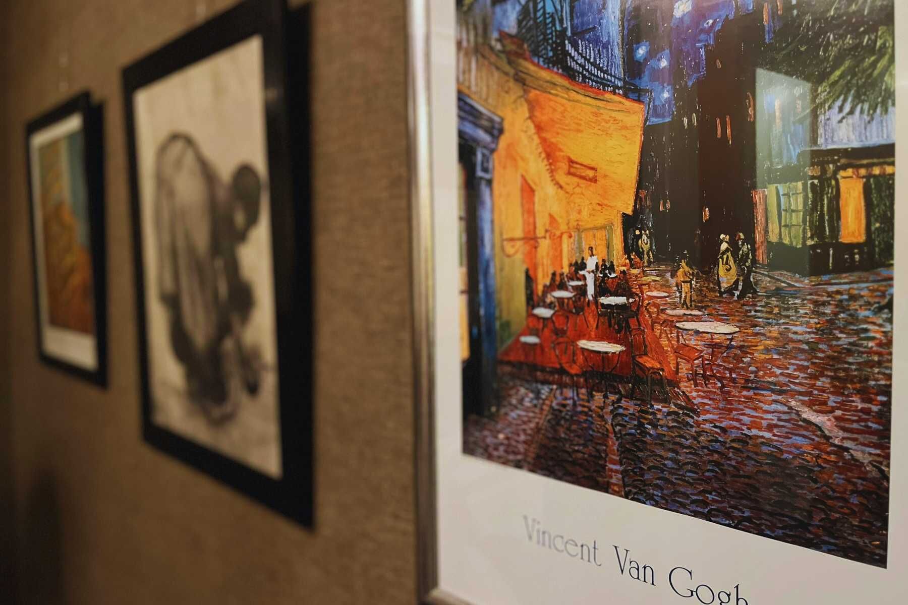 A framed artwork of a café scene by Vincent Van Gogh.