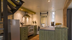 A modern kitchen with a built-in oven, a stainless steel refrigerator, and a wooden island with a bowl of fruit.