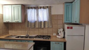 A kitchen with a gas stove, sink, and a refrigerator.