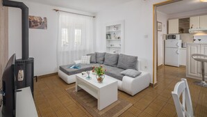 A modern living room with a sofa, coffee table, and a TV. There is a kitchen visible in the background. - Stunning home in Erzisce (Erzisce)