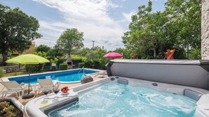 A backyard with a swimming pool, hot tub, and outdoor seating area. - Stunning home in Erzisce (Erzisce)