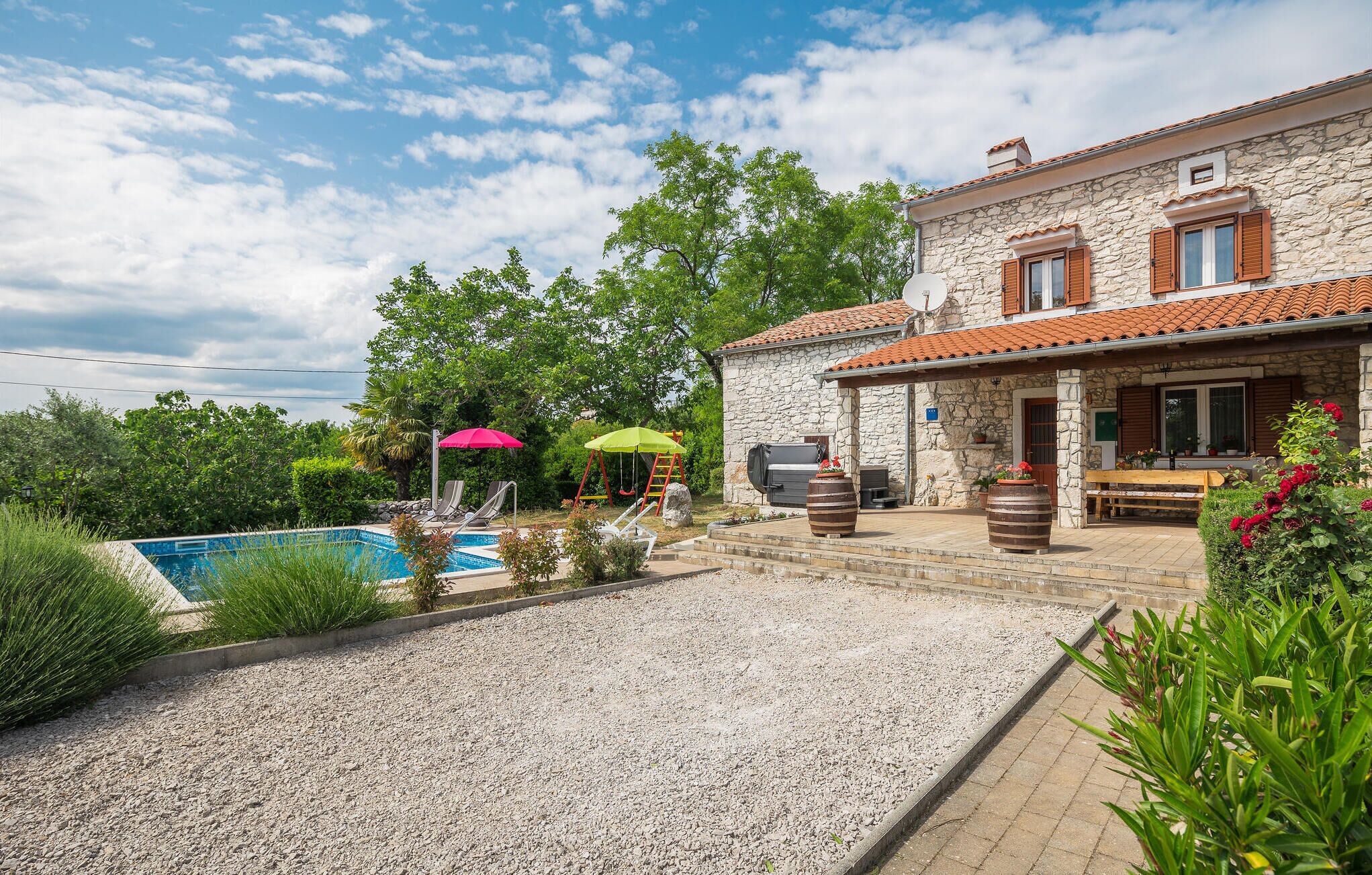 A stone house with a swimming pool, outdoor seating, and a barbecue area.