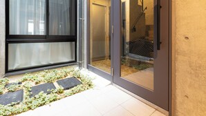 A modern building with large windows and a sliding glass door leading to a covered outdoor area. - Laffitte Ryogoku (Tokyo)
