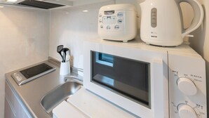 A compact kitchen with a microwave, toaster, and coffee maker on the countertop. - Laffitte Ryogoku (Tokyo)