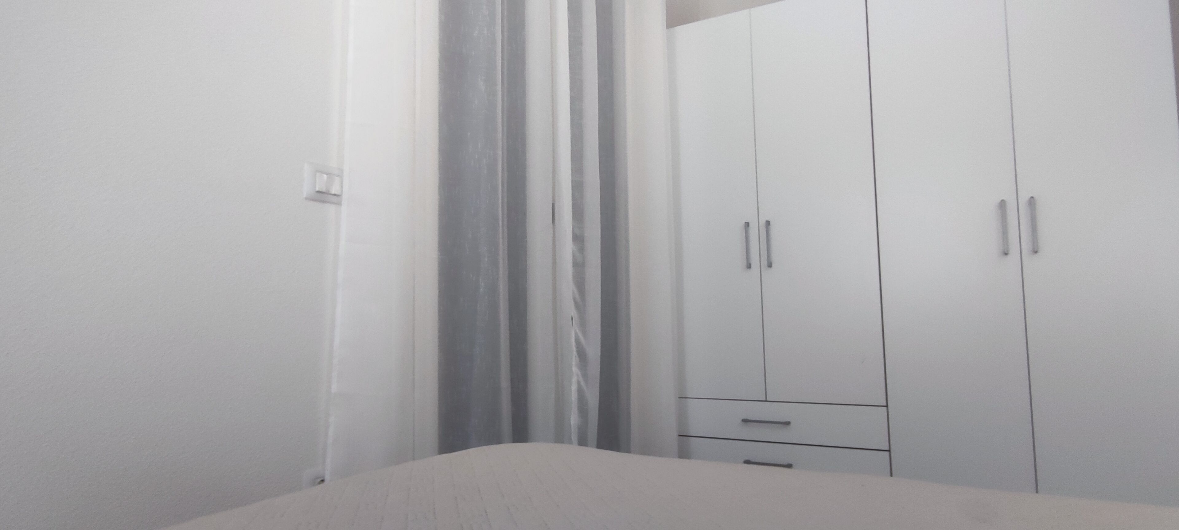 Ein Schlafzimmer mit einem Bett, einem Kleiderschrank und einem Vorhang.