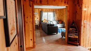 Un interior de madera con un sofá, una estantería y una ventana.