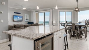 A modern kitchen with a large island, pendant lighting, and a view of the ocean. - Beautiful 3 bedroom, 3 bath condo is located in the popular luxury building, Gateway Grand (Ocean City)