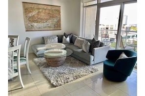 Relax in this stylish living space with a sofa, armchair, and city views through large windows.