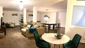 Uma sala de estar com sofá, cadeiras, mesa de jantar e televisão.