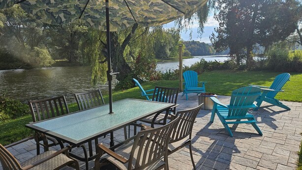 An outdoor patio with a table and chairs, a fire pit, and a view of a lake. - Beau Rivage Waterfront, kayak, SUP, great fishing, swimming, fire pit, updated (Portlandville)