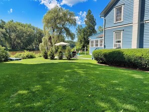 A well-maintained lawn, a large tree, and a blue building with a window.